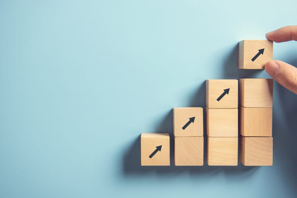 Hand arranging wood block stacking as step stair on paper pink background. Business concept growth success process, copy space.